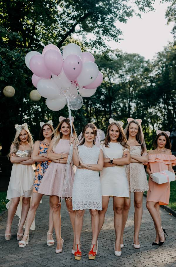 Ομάδα φίλων γυναικών ποζάρουν στον φακό κρατώντας ροζ μπαλόνια