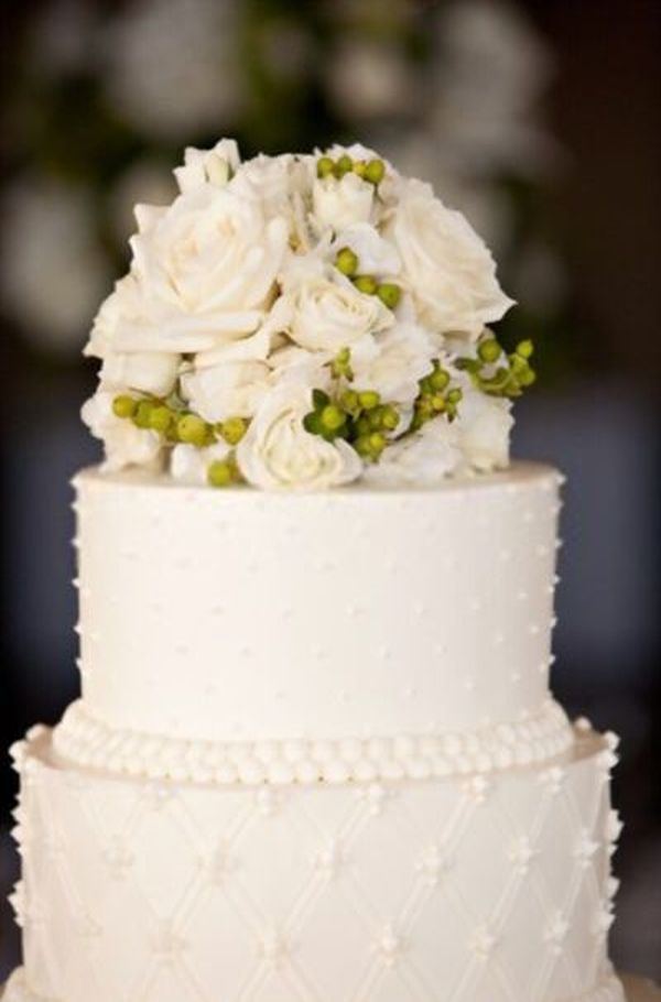 Λευκή γαμήλια τούρτα με λουλούδια στην κορυφή