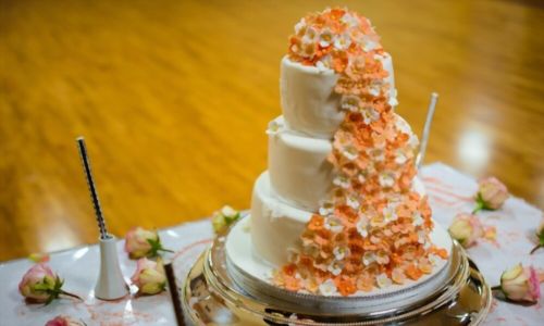Γαμήλια τούρτα πορτοκαλιού με λουλούδια και κεριά