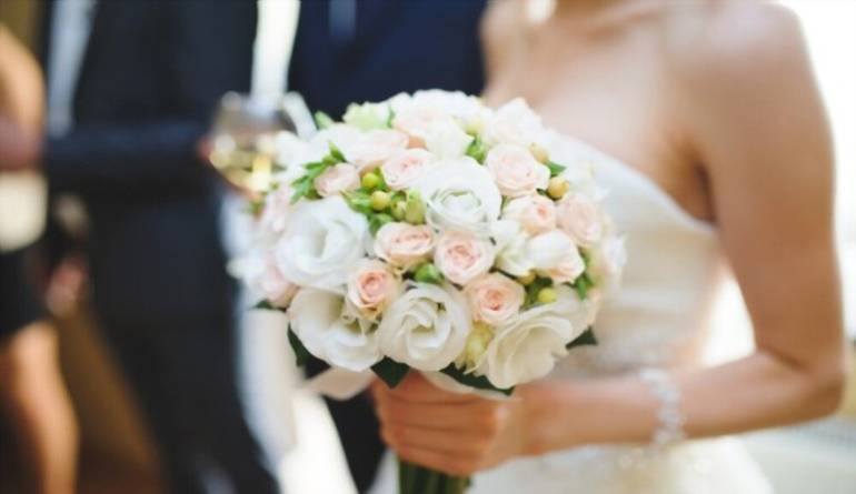 Γαμήλιo μπουκέτο με τριαντάφυλλα στο χέρι της νύφης