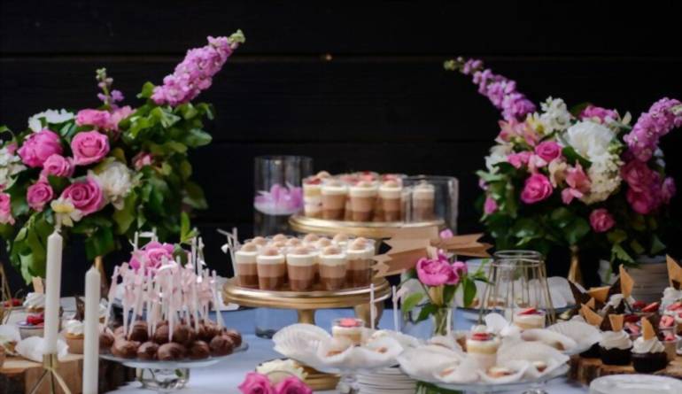 Γλυκά γάμου που στολίζονται με ζουμερά κεράσια και φράουλες και τοποθετούνται στο ξύλινο τραπέζι.