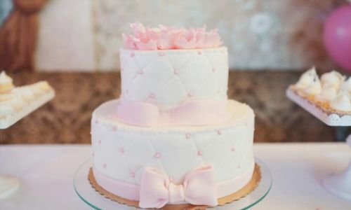 Ροζ μαργαριτάρια και ροζ φιόγκο σε νόστιμο λευκό κέικ