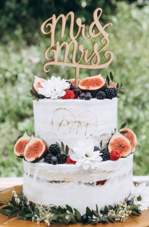 Πολυεπίπεδη γαμήλια τούρτα στο τραπέζι. Λεπτή λευκή διακόσμηση κρέμας, φρούτων και μούρων.