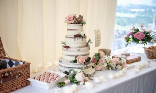 Νόστιμη γαμήλια τούρτα τεσσάρων επιπέδων διακοσμημένη με μούρα και τριαντάφυλλα
