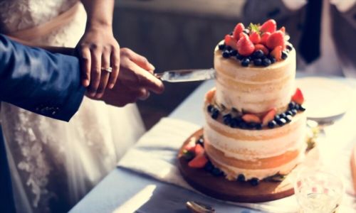 Ζευγάρι χέρια που κόβουν τη γαμήλια τούρτα