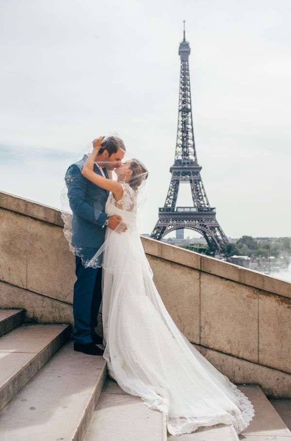 Νιόπαντρο ζευγάρι φιλιέται τρυφερά με φόντο τον πύργο του άιφελ