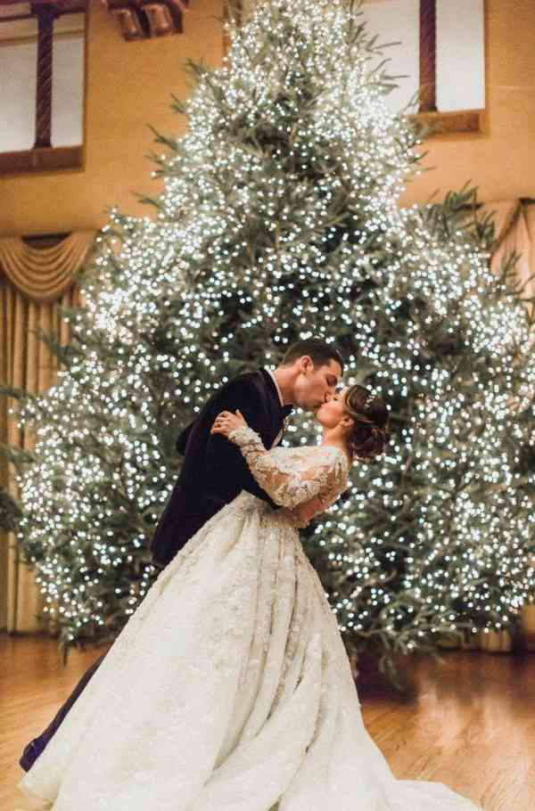 Νίόπαντρο ζευγάρι φιλιέται με φόντο το χριστουγεννιάτικο δέντρο