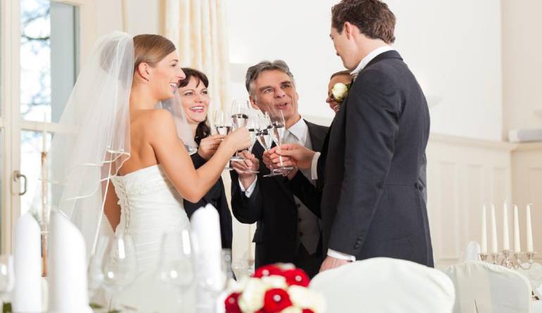 Νύφη, γαμπρός και καλεσμένοι σε γάμο τσουγκρίζουν τα ποτήρια τους.