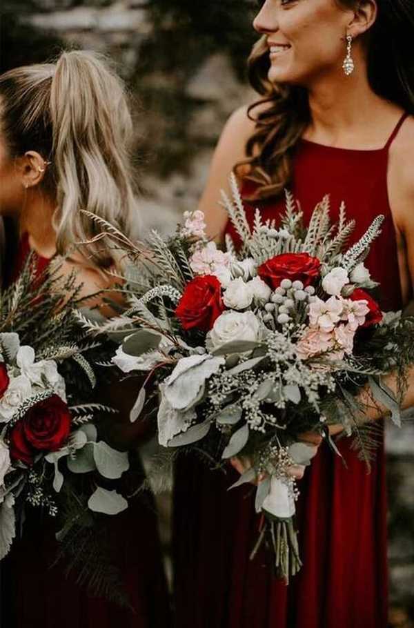 Λαμπερές παράνυφες με κόκκινα φορέματα κρατάνε χειμερινα λουλούδια για γάμο