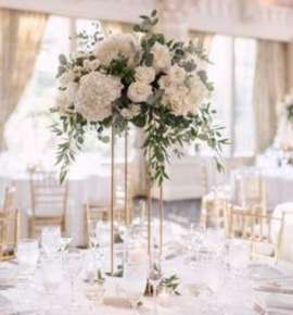 Διακόσμησή γάμου σε τραπέζι με μεγάλες ανθοστήλες λουλουδιών