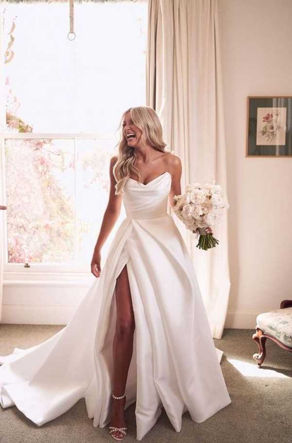 Χαμογελαστή νύφη με υπέροχο νυφικό φόρεμα και ανθοδέσμη στο χέρι