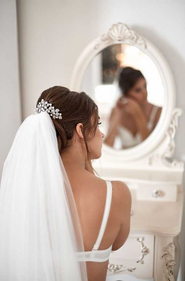 Προετοιμασία νύφης στον καθρέφτη φορώντας νυφικά εσώρουχα και πέπλο