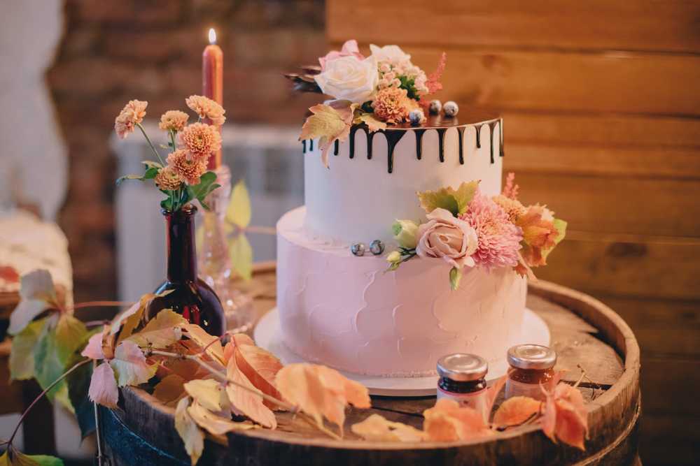 Λευκή τούρτα γάμου με λουλούδια πάνω σε ξύλινο βαρέλι