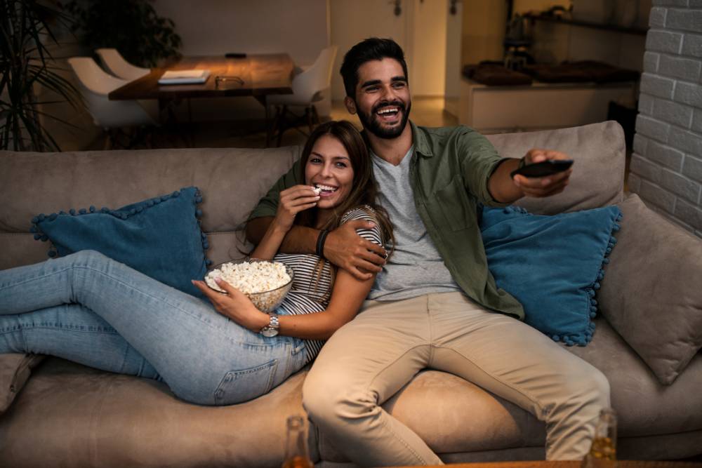 Χαλαρό ζευγάρι τρώει ποπ κόρν και βλέπει τηλεόραση
