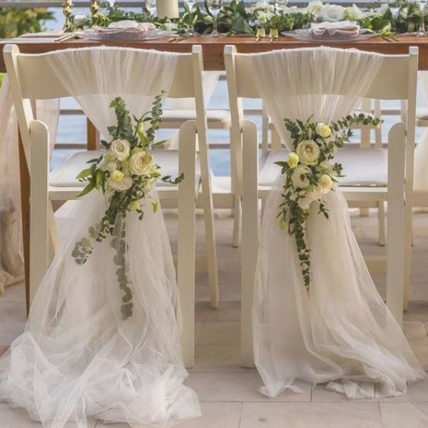 Καρέκλες σε σπίτι για γάμο με γάζα και λουλούδια